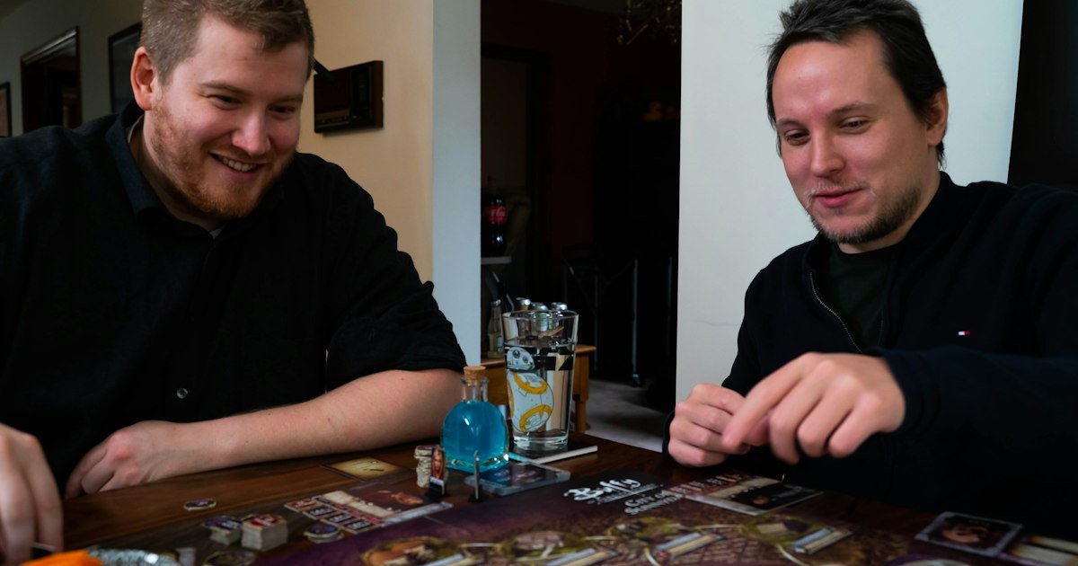 Two friends smiling while playing a board game