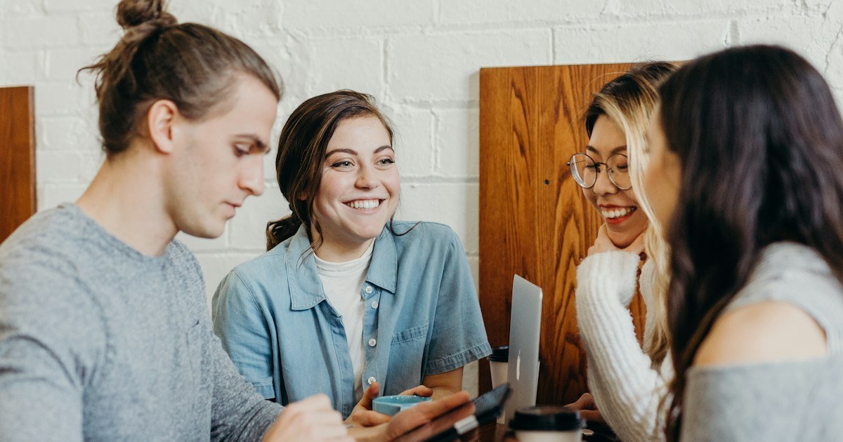 Group of young friends laughing together at a table