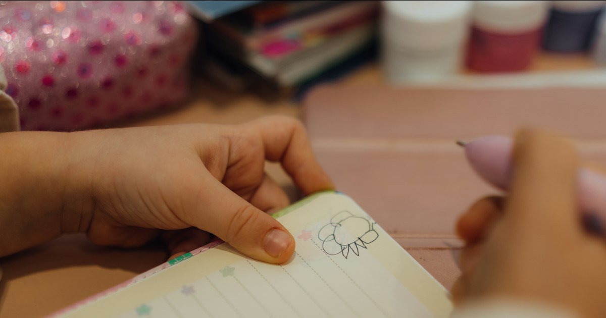 Hands writing in a small notebook at a table