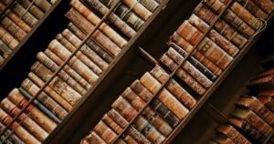 Rows of old leather-bound books on wooden library shelves