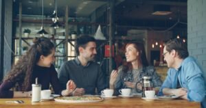 Group of friends chatting and laughing around a café table