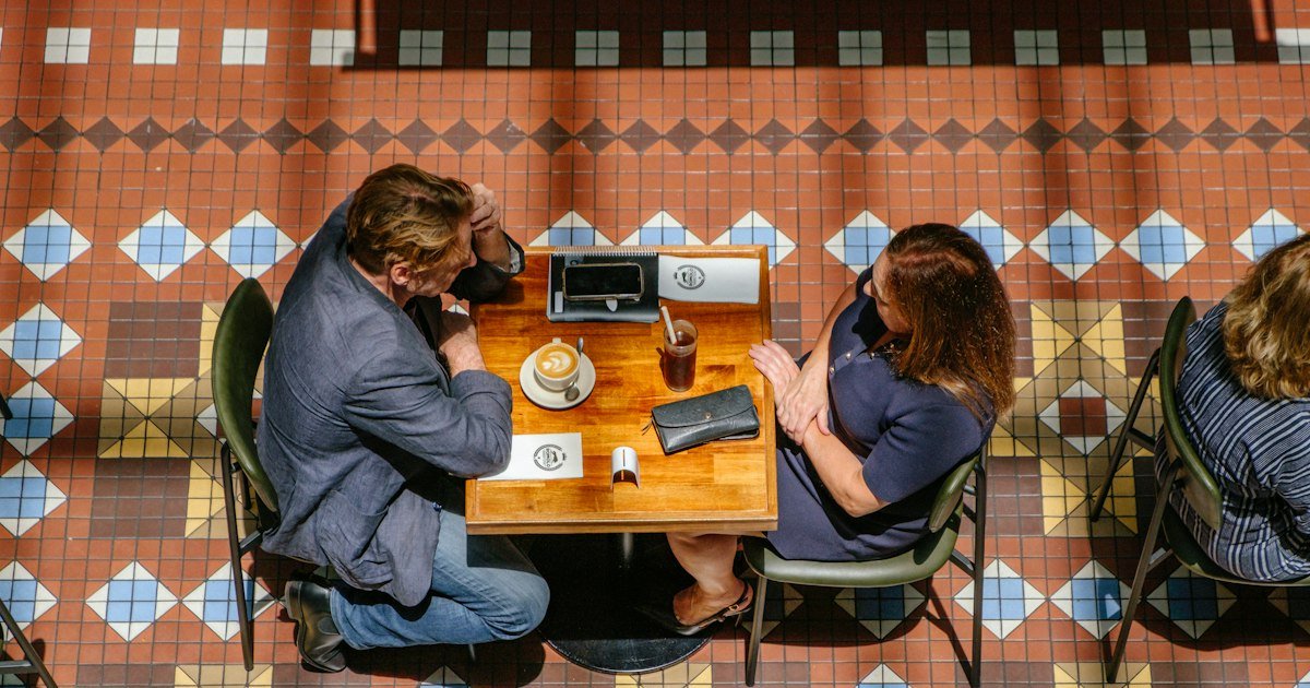 Two people sitting quietly at a café table seen from above