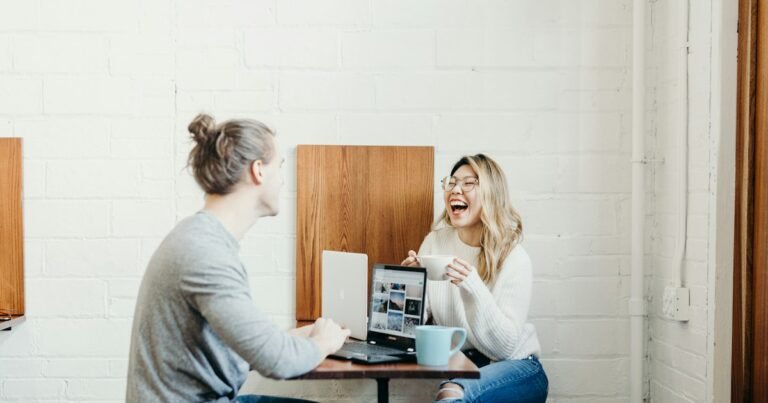 Two people making relaxed eye contact and laughing across a table