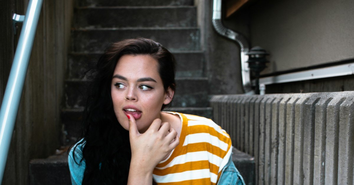 Young woman sitting on steps with a shy, thoughtful expression