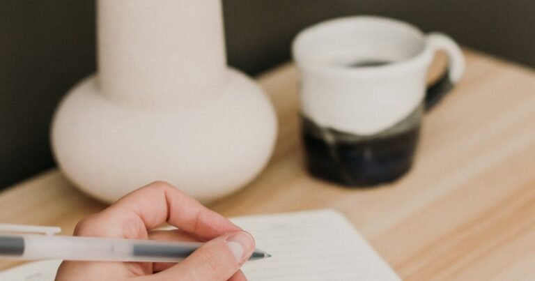 Hand writing in a journal next to a cup of coffee