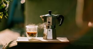 Cup of coffee and a moka pot in warm morning sunlight