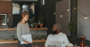 Woman holding a laptop talking with a colleague in a modern office
