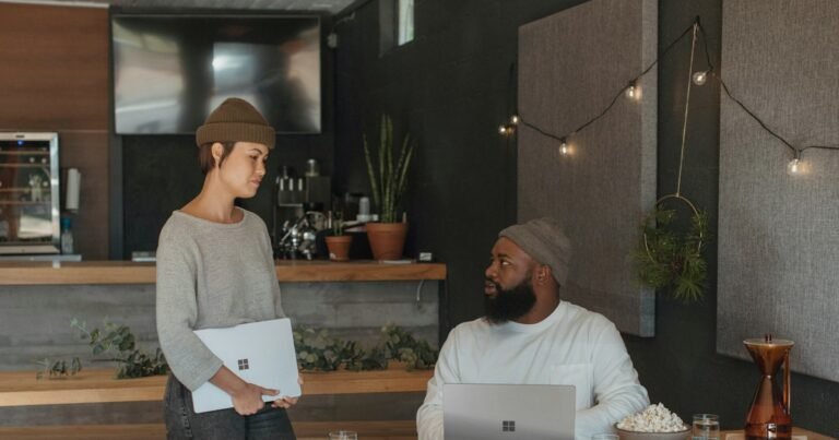 Woman holding a laptop talking with a colleague in a modern office