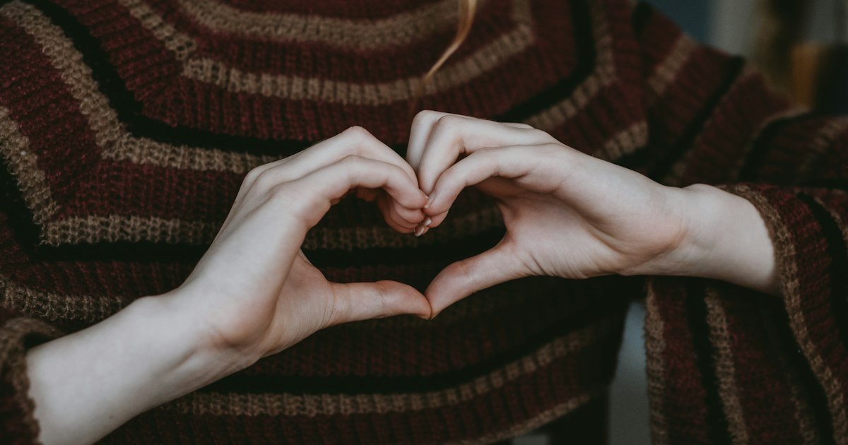 Hands forming a heart shape in front of a cosy sweater