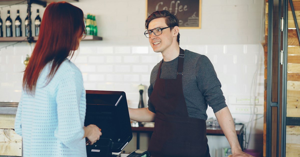 Customer ordering at a café counter from a friendly barista