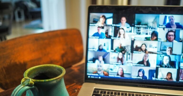 Laptop showing a group video call next to a cup of coffee