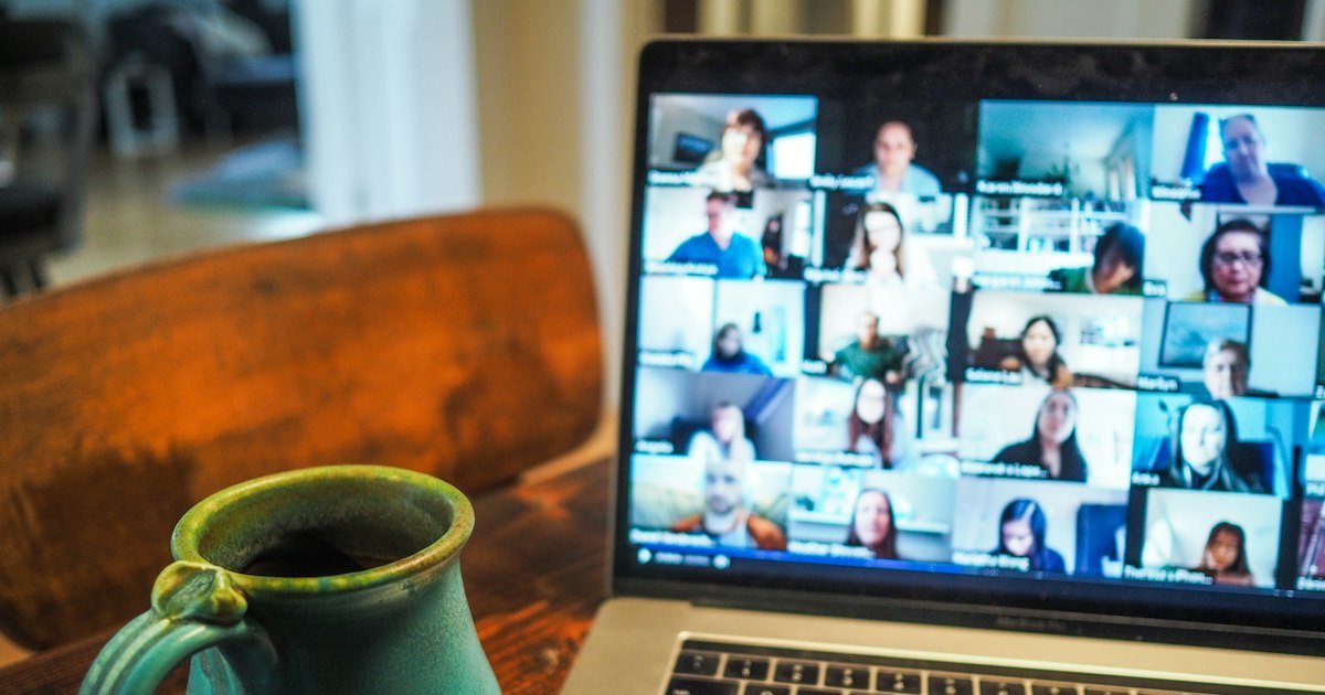 Laptop showing a group video call next to a cup of coffee