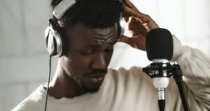 Man wearing headphones speaking into a studio microphone